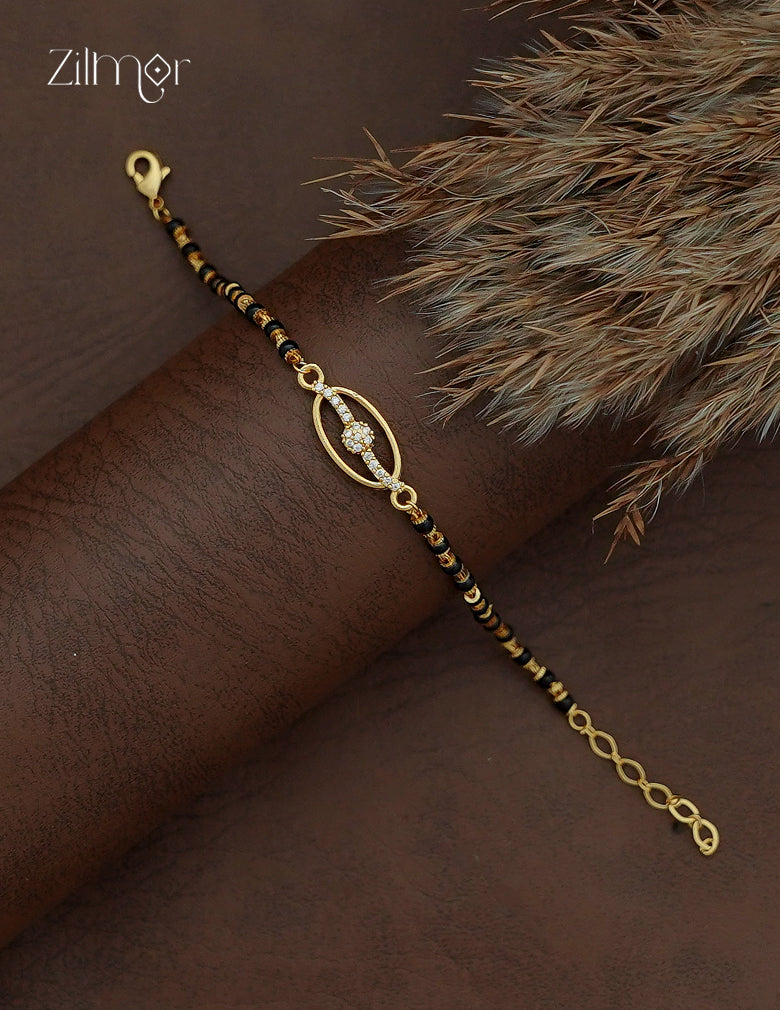 Diagonal view of black bead mangalsutra bracelet with gold-tone spacers, AD stone oval motif and lobster clasp