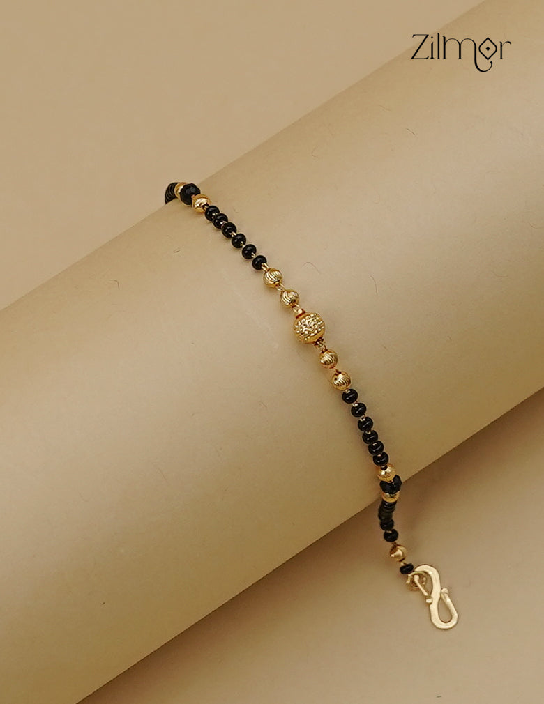 18K gold plated black bead mangalsutra bracelet laid open, showing gold-tone accents and textured centre bead