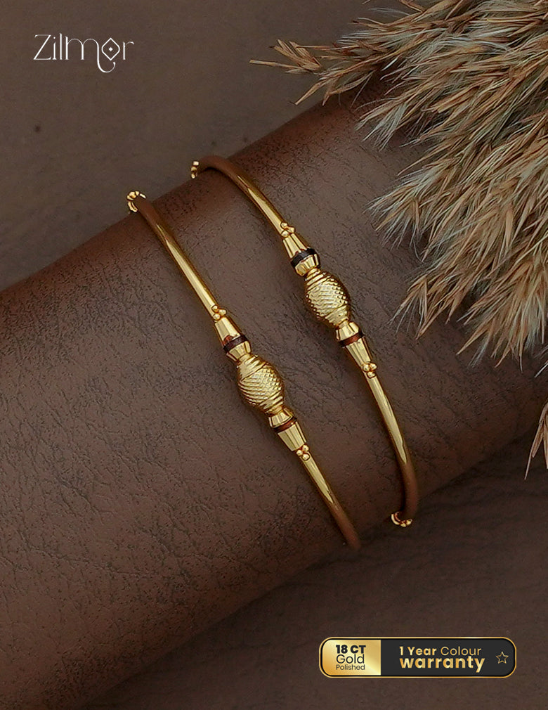 Zilmor 18K gold plated bangle pair with textured oval centres, tapered decorative sections and slim gold-tone bands.