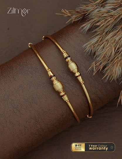 Zilmor 18K gold plated bangle pair with textured oval centres, tapered decorative sections and slim gold-tone bands.