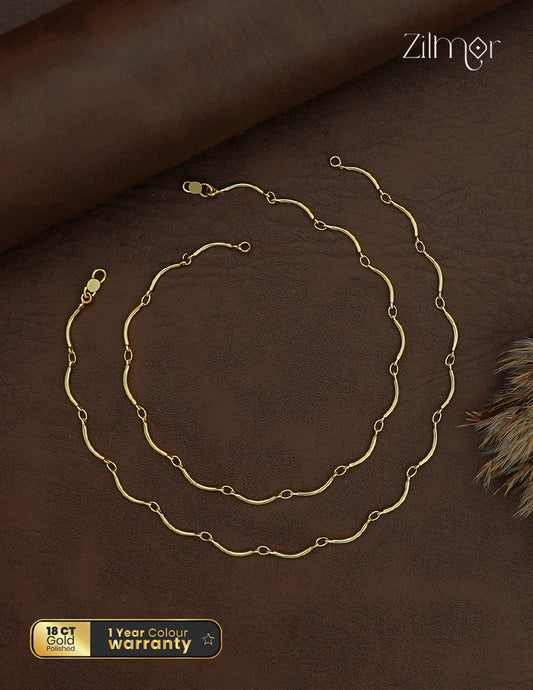Zilmor 18K gold polished anklet pair with curved chain links and lobster-claw clasps on a brown background