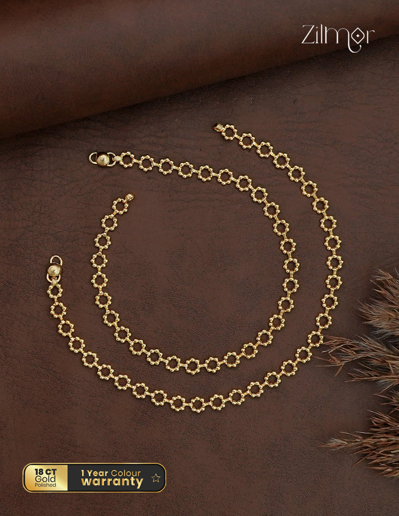 Zilmor 18K gold polished anklet pair with textured open circular links on a brown background