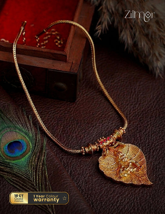 Gold necklace with leaf pendant on a dark surface, Zilligor brand visible