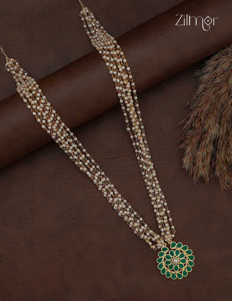 Long layered pearl necklace with green Kemp-style stone pendant on a dark background