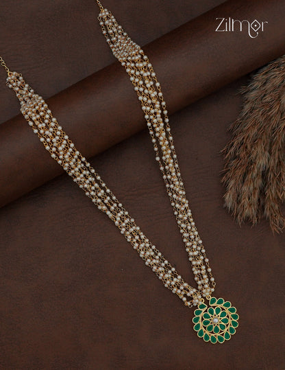 Long layered pearl necklace with green Kemp-style stone pendant on a dark background