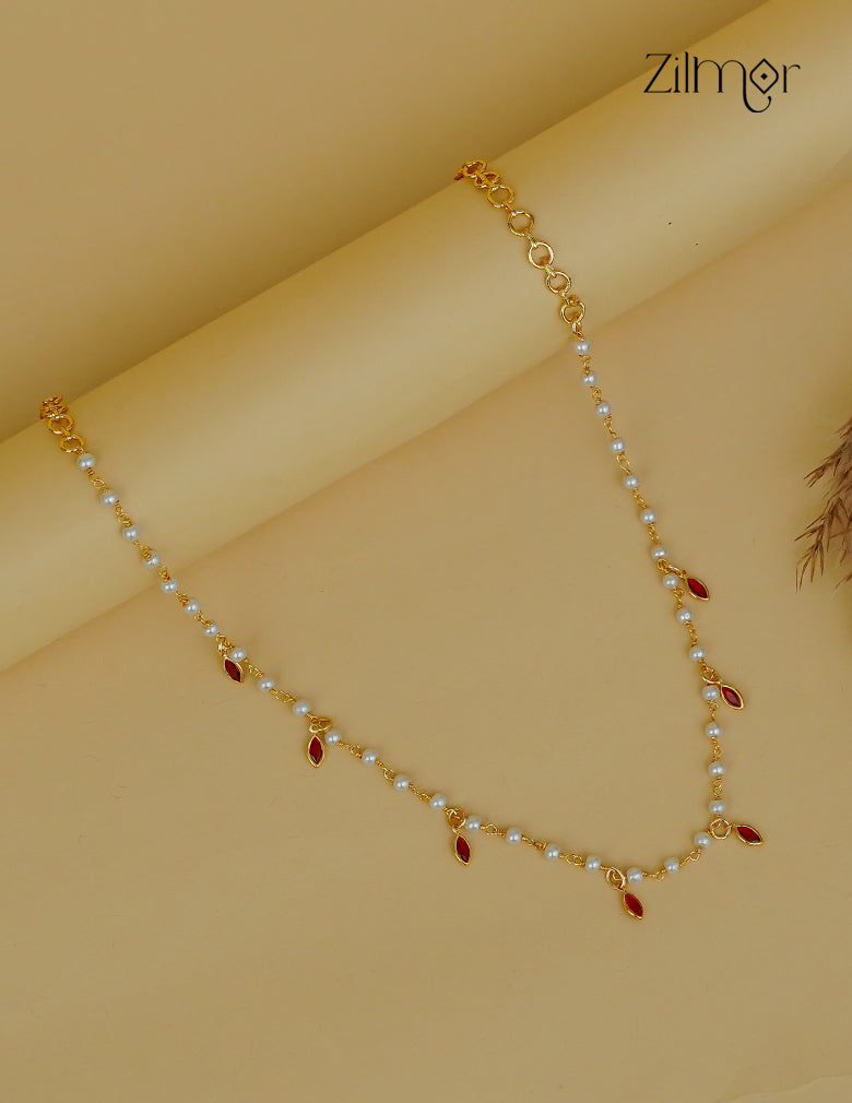 Gold necklace with pearls and red stones on a beige background, featuring the brand 'Zahra'.