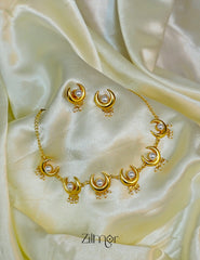Close-up of the lustrous pearl set within the delicate gold half moon pendant.